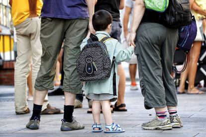 Dos mujeres llevan de la mano a un niño en el inicio de curso.