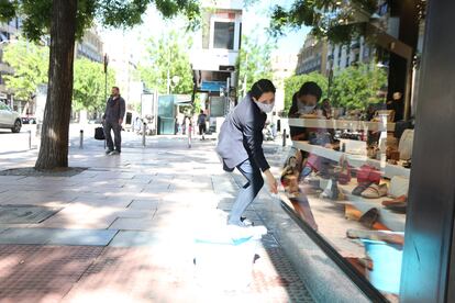 A worker cleaning the display window of a shoe store in Madrid.