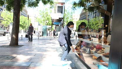 A worker cleaning the display window of a shoe store in Madrid.