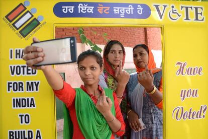 Tres mujeres se fotografían enseñando el dedo manchado de tinta tras votar este domingo en Amritsar.