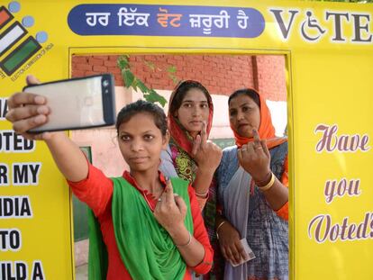 Tres mujeres se fotografían enseñando el dedo manchado de tinta tras votar este domingo en Amritsar.