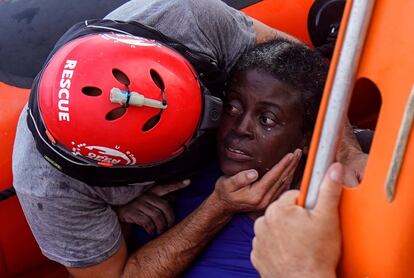 Un miembro de Open Arms abraza a una mujer rescatada de una balsa en el Mediterráneo junto a los cuerpos de otra mujer y un bebé ahogados. 