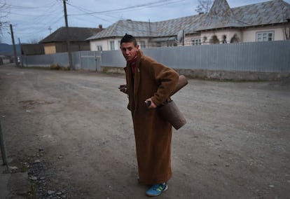 A young man puts bells around him, as he prepares to attend a rehearsal as " moshoi " to drive away evil spirits, on the street in Luncavita village on December 16, 2015. Organized in groups of twenty people, they go from house to house, performing songs and dances which combines pagan and Christian elements before Christmas. / AFP / DANIEL MIHAILESCU / TO GO WITH AFP STORY