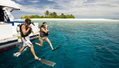Dos buceadores saltando al agua en Maldivas, en el océano Índico.