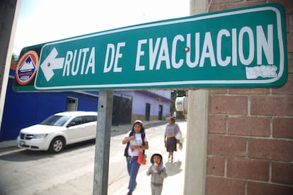 El Popocatépetl es uno de los volcanes más activos del mundo, situado a unos 70 kilómetros de la capital y entre los Estados de Puebla, Morelos y Estado de México. Sus fumarolas se han convertido en parte del paisaje del centro de México. En la imagen, dos mujeres y un niño caminan por una de las calles del pueblo de Hueypan, en el Estado de Morelos, una de las comunidades aledañas a la estructura geológica. 