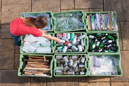 Una mujer tira una lata en un contenedor para su reciclaje.