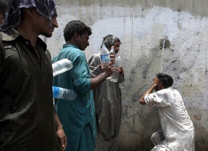 Um homem tenta se hidratar em uma torneira pública em Karachi, no sul do Paquistão, enquanto outros aguardam para encher suas garrafas. O Governo construiu acampamentos hospitalares improvisados nas ruas da cidade onde mais de 400 pessoas morreram em quatro dias.