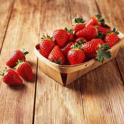Punnet of strawberries on wooden table