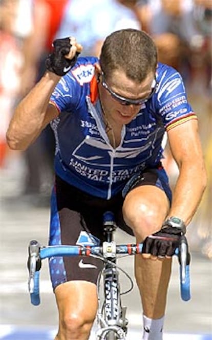 Lance Armstrong cruza la meta con el puño en alto para celebrar su victoria.