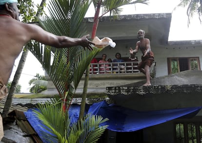 Un voluntario lanza un paquete de pan hacia una familia atrapada en una zona inundada de Chengannur, al sur de Kerala, el 19 de agosto de 2018.