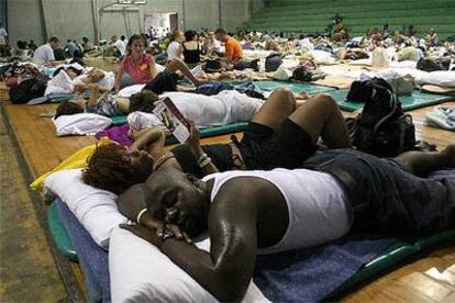 Decenas de turistas esperan la llegada del huracán Emily albergados en un gimnasio de Cancún.