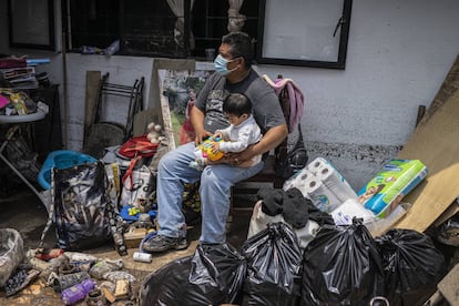 Un hombre cuida de un bebé al exterior de su casa que quedó dañada por las fuertes lluvias de la tarde el lunes en Atizapán, Estado de México