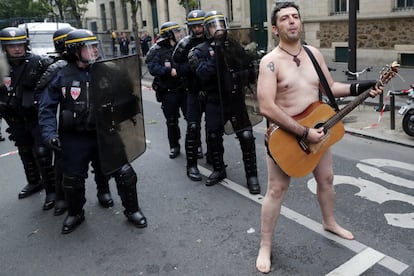 Un manifestante toca la guitarra desnudo frente a varios policías antidisturbios durante una primera jornada de huelgas y protestas contra la reforma laboral por decreto del presidente francés, Emmanuel Macron, en París (Francia).