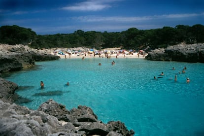 Es Talaier (Ciudadela, Menorca) Una joya engarzada en la costa milagrosa, por intocada, del Migjorn (sur) menorquín. Con la cegadora blancura en la arena y aguas remansadas y someras que se desarrollan brillantes bajo el sol, la sensorial cala de Es Talaier parece una piscina casi a la sombra de los pinos. Los roquedos que franquean sus escasos 50 metros de longitud impiden el fondeo de embarcaciones de recreo y ese rastro de posidonia que dejan en la orilla. Es interesante llegar a partir de las seis de la tarde, a contracorriente turística. <p><b>Acceso: </b>desde el 2 de mayo circulan autobuses desde Ciudadela hasta el arenal de Son Saura. Novedad de este año son las pasarelas que protegen las dunas de Son Saura, tras las que hay que bordear la punta des Pinar por el Camí de Cavalls hasta la cala (unos 15 minutos de caminata).</p>