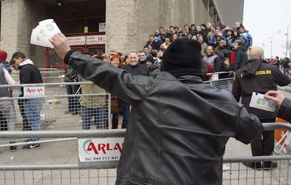 Un aficionado eufórico muestra las entradas que acaba de adquirir a aquellos que todavía siguen en la cola