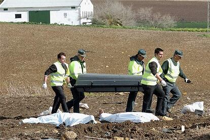 Agentes de la Guardia Civil y empleados de la funeraria retiran uno de los cadáveres del accidente de Écija.