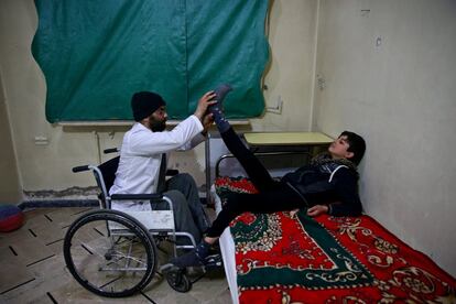 Ziad (derecha), de 14 años, acude a una sesión de fisioterapia junto a Haitham, de 35, quien sufrió una lesión de médula espinal durante el conflicto sirio que le dejó parapléjico, en un centro de rehabilitación en Douma, el principal bastión de los rebeldes en las afueras de Damasco (Siria).
