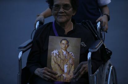 Una mujer sostiene un retrato del rey Bhumibol Adulyadej de Tailandia mientras espera en la cola para mostrar sus respetos al fallecido monarca en el Gran Palacio en Bangkok (Tailandia).