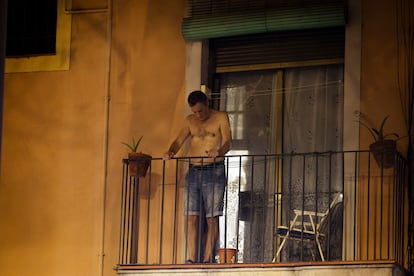 Un hombre se asoma al balcón en el barrio de El Raval, en Barcelona, durante una de las tórridas noches de agosto.