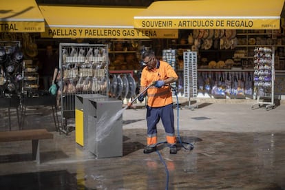 Un trabajador de la contrata municipal limpia unas papelera este martes en una calle del centro de Valencia.