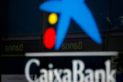 Vista de una oficina de CaixaBank y otra de Bankia reflejada en el cristal.