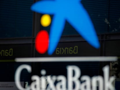 Vista de una oficina de CaixaBank y otra de Bankia reflejada en el cristal.