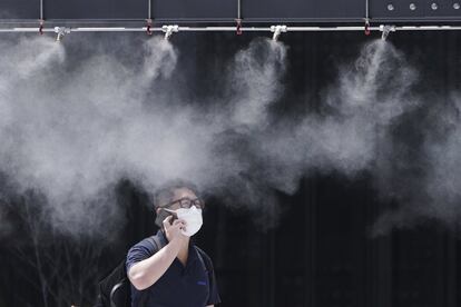 Un hombre pasa junto a un vaporizador de neblina fría para refrescarse, en Tokio (Japón).