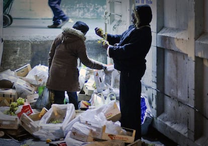 Dos mujeres rebuscan comida en buen estado entre los restos de fruta que han sobrado de la venta al por mayor en Mercamadrid.