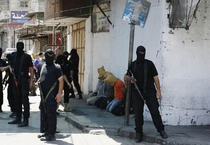 Terroristas de Hamás vigilan a seis palestinos arrodillados a los que asesinaron después.