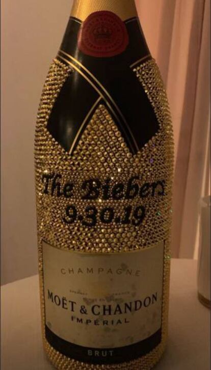 Una botella de champán Moet&Chandon cubierta de cristales con el nombre de los novios y la fecha de la boda.