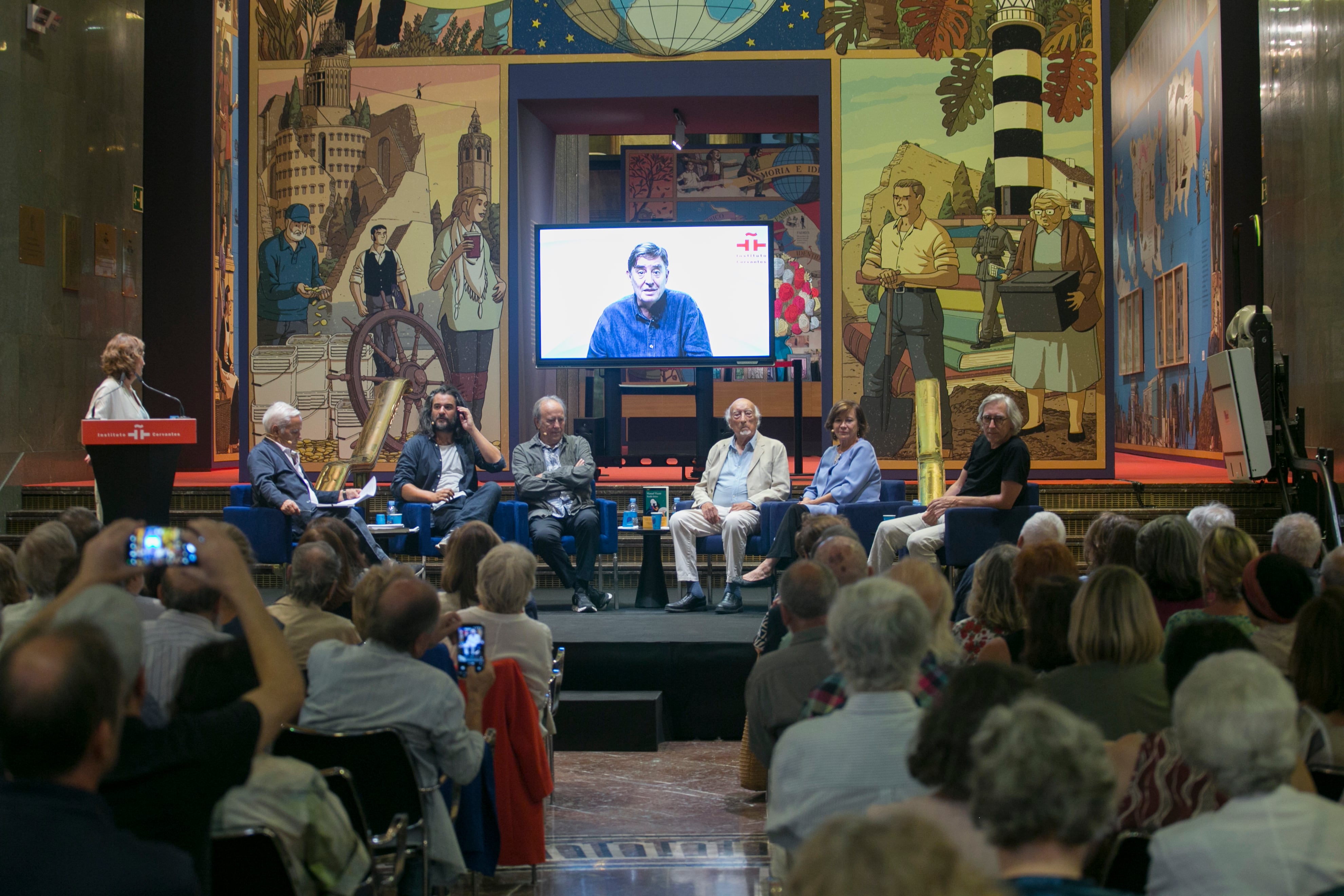 Homenaje a Manuel Vicent, con Luis García Montero interviniendo en la distancia.