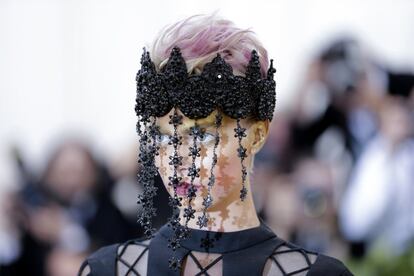 Cara Delevingne con un diseño de alta costura de Dior y un tocado negro del que caen varias tiras con pequeñas flores.