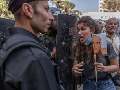 La policía cierra el paso a una palestina que protesta con una foto de NIzar Banat, el jueves en Ramala.