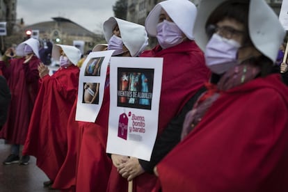 Varias mujeres vestidas como las mujeres destinadas a la reproducción de la serie televisiva 'El cuento de la criada' participan en una manifestación organizada por la Asamblea Feminista de Valencia en la plaza de los Pinazo, en Valencia. Este es uno de los actos que se celebran con motivo del Día Internacional de la Mujer que este 2021 está marcado por la ausencia de grandes movilizaciones, como en años anteriores, que han sido sustituidas por concentraciones en la calle con restricciones de aforo o protocolos de seguridad contra el coronavirus.