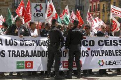 Varios efectivos de la policía ante una de las pancartas que se han visto durante la manifestación llevada a cabo hoy por el centro de León, para rechazar los 1.320 despidos que planea el Banco Ceiss, en una protesta a la que se han sumado autobuses llegados de toda España y en la que han exigido "despido cero".