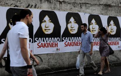Peatones en el centro de Roma caminan junto a una pared empapelada con pósters de la mujer azerí condenada a la pena de lapidación, en los que se puede leer: "Salvemos a Sakineh".