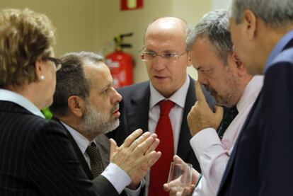 Los portavoces del PSOE y del PNV, Francisco Fernández Marugán (a la izquierda) y Pedro Azpiazu (a la derecha), discuten en la Comisión de Presupuestos del Congreso, rodeados de diputados y letrados.
