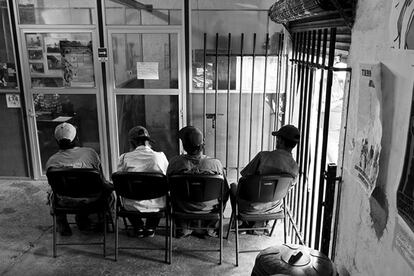 Cuatro hombres esperan su turno para ingresar al comedor.