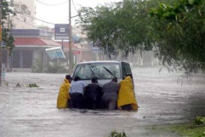 Habitantes de Cancún intentan mover un vehículo atrapado entre las aguas, tras lal fuertes lluvias provocadas por la entrada del huracán Wilma.