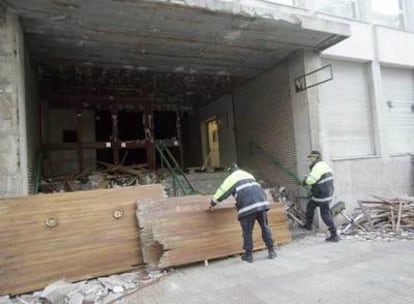 Dos policías locales utilizan las puertas destrozadas del juzgado de Sestao para hacer una barrera frente al edificio atacado.