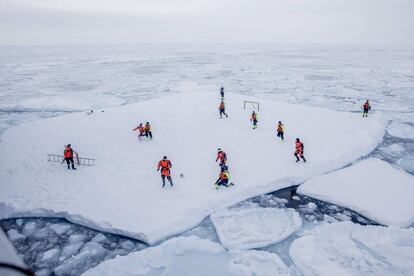 Miembros de la tripulación del KV Svalbard y científicos del Instituto Noruego de Investigación Marina juegan al fútbol sobre una placa de hielo en el mar de Groenlandia mientras dos guardias vigilan que no se acerquen osos polares. 