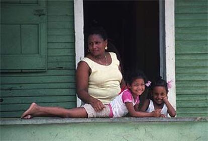 Familia dominicana en el porche de su casa, una construcción de madera del característico estilo victoriano caribeño, en Puerto Plata, al norte del país.