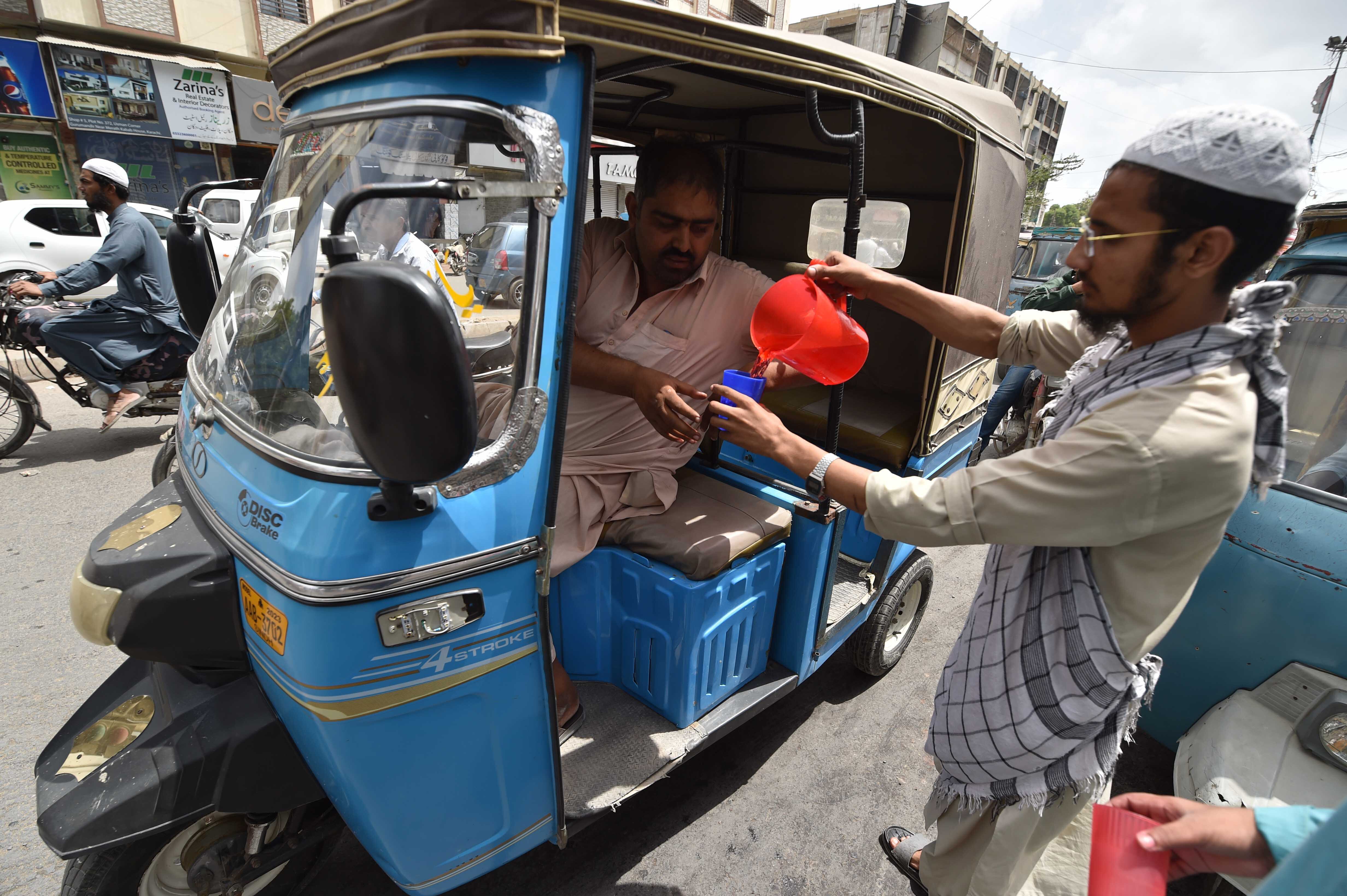 Un voluntario ofrece bebidas frias, el 3 de junio en una carretera de Karachi (Pakistán).