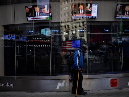 Un hombre pasa por delante de un escaparate con imágenes de un discurso del presidente de EE UU, Donald Trump, en Nueva York. 