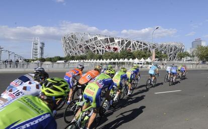 Los ciclistas pasan junto al Nido de P&aacute;jaro, en la Vuelta a Pek&iacute;n.