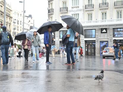 Varias personas pasean bajo la lluvia, el martes 23 de mayo, en el centro de Madrid.