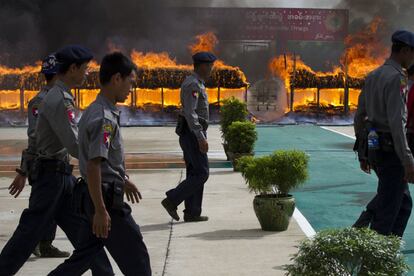 Oficiales de policía pasan por delante del fuego durante una ceremonia de destrucción de drogas narcóticas incautadas en las afueras de Yangon, Myanmar.