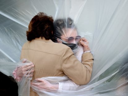 Una mujer abraza a su abuela a través de un paño de plástico colgado en un tendedero casero en Nueva York, el 24 de mayo de 2020.