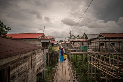 A woman walks with a child on the streets of the town of Iceland in the Peruvian Amazon, on December 12, 2024.