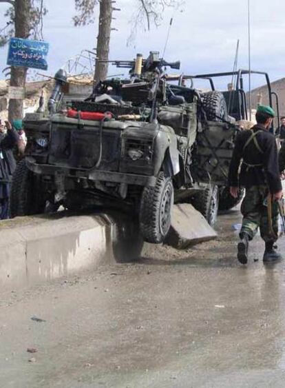 Un soldado del Ejército afgano observa un vehículo de la OTAN destrozado tras un atentado suicida ocurrido en Kandahar, el pasado domingo.